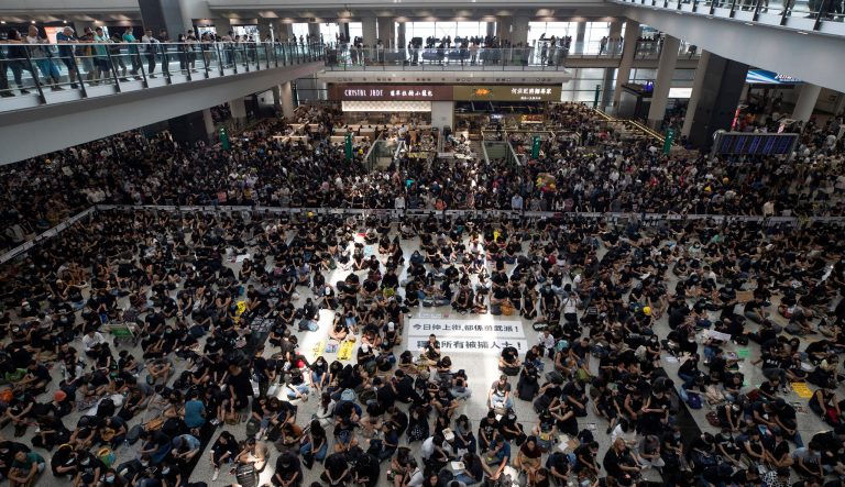 Protesters surround banners that read "Those charge to the street on today is brave!," center top, and "Release all the detainees!" during a sit-in rally at the arrival hall of the Hong Kong International airport in Hong Kong, Monday, Aug. 12, 2019.