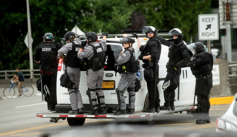 Police officers ride on the side of a van as right-wing demonstrators and counterprotesters gather in Portland, Oregon.