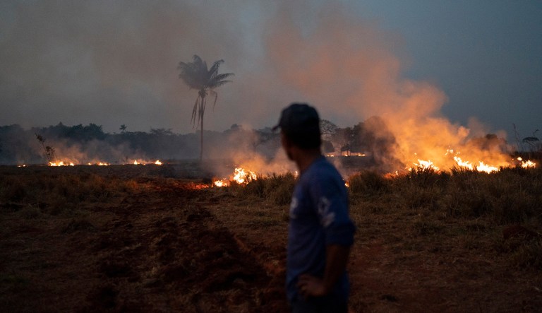 Neri dos Santos Silva watches an encroaching fire threat after digging trenches to keep the flames from spreading to the farm he works on, in the Nova Santa Helena municipality, in the state of Mato Grosso, Brazil.