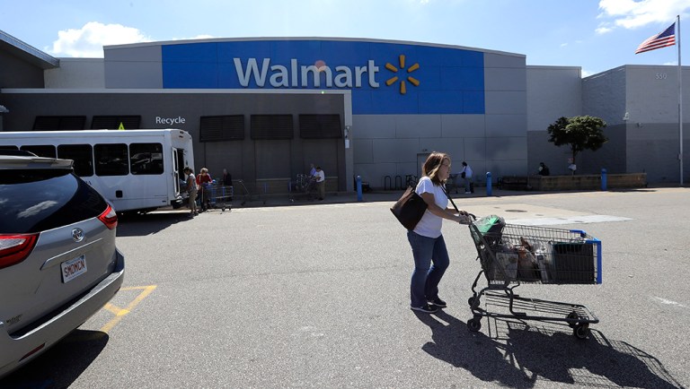 A customer pushes a shopping cart outside a Walmart.
