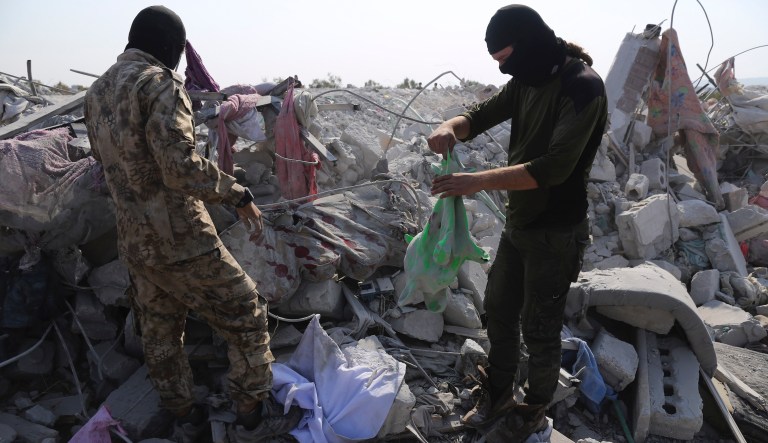 People look at a destroyed houses near the village of Barisha, in Idlib province, Syria, Sunday, Oct. 27, 2019, after an operation by the U.S. military which targeted Abu Bakr al-Baghdadi, the shadowy leader of the Islamic State group.