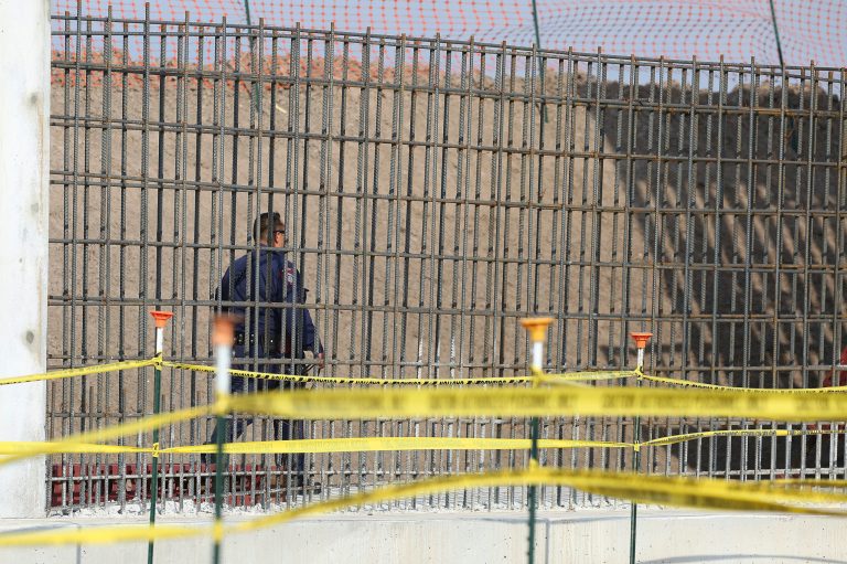A McAllen K-9 police officer walks past rebar that will make up the border wall south of Donna, Texas.