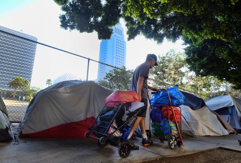 A homeless man in July moved his belongings from a street behind Los Angeles City Hall as crews prepared to clean the area. California Gov. Gavin Newsom blamed the Trump administration for withholding data that is blocking the release of $650 million aid to combat homelessness. The administration countered that Newsom can use the money whenever he wants.