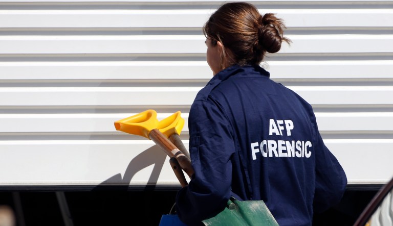 A police investigator arrives with a shovel at a home at Guildford in suburban Sydney after about 800 federal and state police officers raided more than two dozen properties as part of the operation Thursday, Sept. 18, 2014. Australian police detained 15 people earlier on Thursday in a major counterterrorism operation, saying intelligence indicated a random, violent attack was being planned on Australian soil.