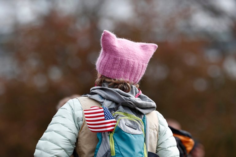 Protester wears a pin stocking pussy hat while carrying an American flag on her pack during a march for science Saturday, April 22, 2017, in Denver.