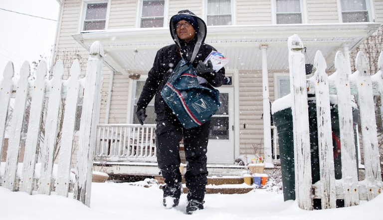 U.S. Postal Service mail carrier Willian Heredia delivers mail during a snowstorm in Catonsville, Md.