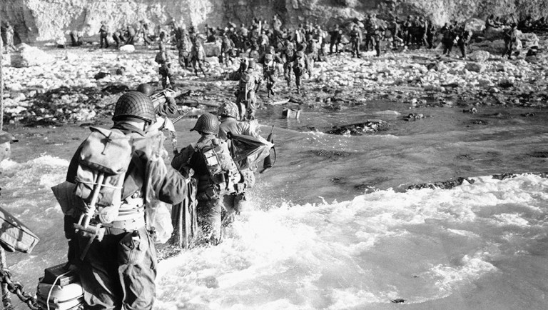 U.S. troops wade through the surf on their way from the landing craft the shores of Normandy, France, on June 14, 1944.