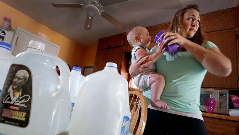 In this Aug. 19, 2015 photo, Emily Webb gives her son, Oliver, a drink of water from her supply of drinking water at their home in Pretty Prairie, Kan.