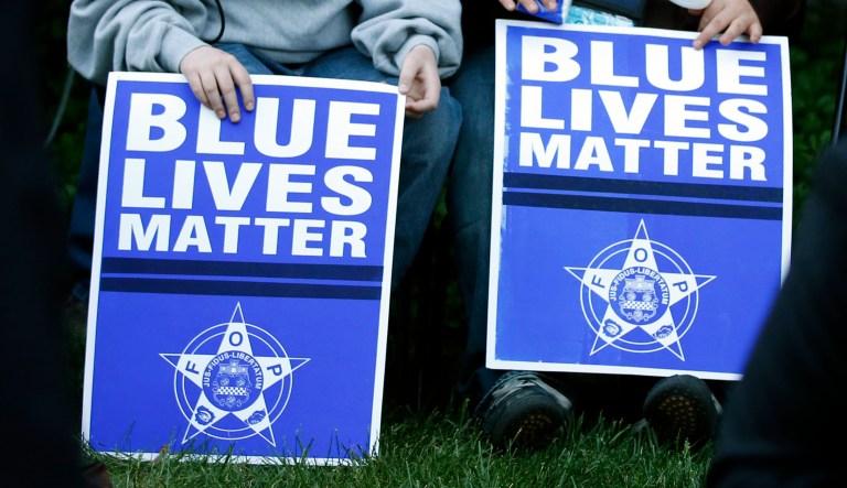 Two people hold signs that say "Blue Lives Matter."