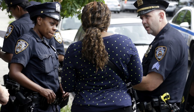 Police officers talk with a woman who had her phone stolen in the Brownsville section of Brooklyn, New York, Tuesday, Aug. 13, 2013. A federal judge's stinging rebuke of the police department's stop-and-frisk policy as discriminatory could usher in a return to the days of high violent crime rates and end New York's tenure as "America's safest big city," Mayor Michael Bloomberg warned.