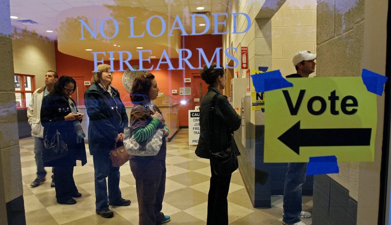 Behind a sign barring loaded firearms in the building, people stand in line to cast their votes on Election Day as the polls opened at a precinct at the Wake County Firearms Education and Training Center in Apex, N.C., on Nov. 6, 2012.