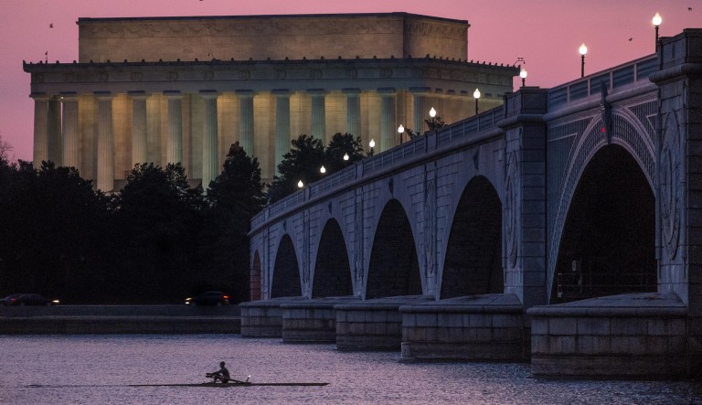 A solitary rower skims across the Potomac River past the Lincoln Memorial and under the Memorial Bridge at sunrise in Washington, Friday, March 21, 2014. 