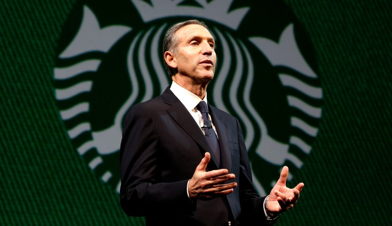 Then-Starbucks CEO Howard Schultz speaks in front of the Starbucks logo during the company's annual shareholders meeting in Seattle.