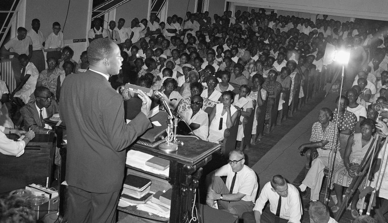 Martin Luther King, Jr., Atlanta minister and leader of the desegregation movement, left, talks to a packed church gathering. (AP Photo)