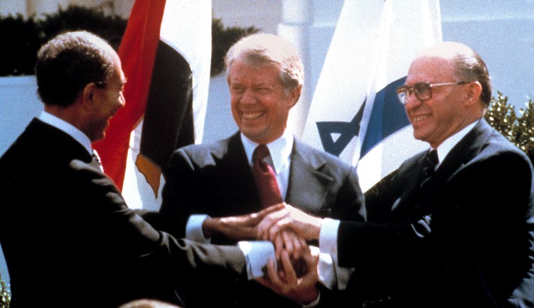 Egyptian President Anwar Sadat, left, President Jimmy Carter, and Israeli Prime Minister Menachem Begin clasp hands on the North lawn of the White House as they completed signing of the peace treaty between Egypt and Israel in Washington. 