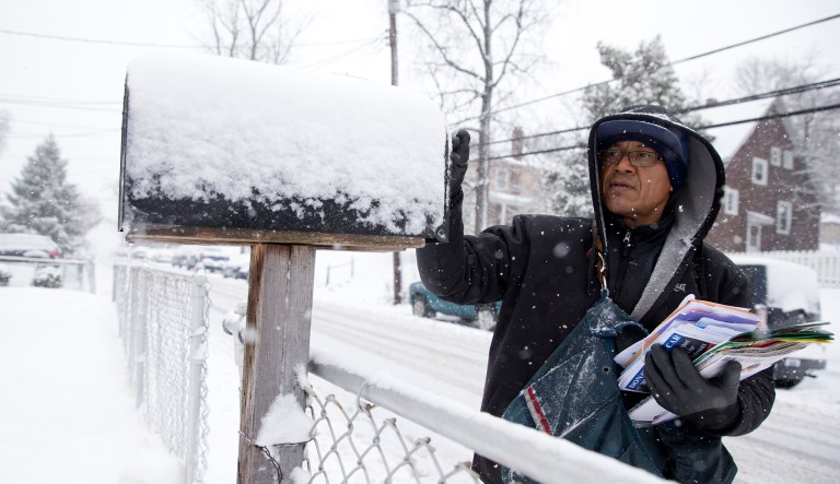 U.S. Postal Service mail carrier Willian Heredia delivers mail during a snowstorm in Catonsville, Md.