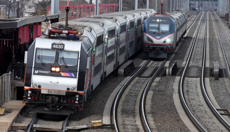 An Amtrak train passes a New Jersey Transit train stopped to discharge and board passengers along Amtrak's Northeast Corridor. 
