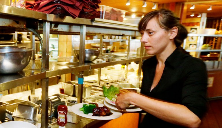 A waitress picks up a food order from the kitchen as she works during lunchtime.
