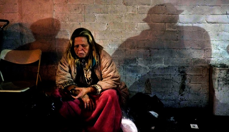 In this March 21, 2013, file photo, a homeless woman has a bite to eat in the Skid Row area of Los Angeles. Reducing poverty has emerged as the key theme in California after state lawmakers moved closer to raising the minimum wage, expanding healthcare to immigrants, and allowing child care providers to unionize.  