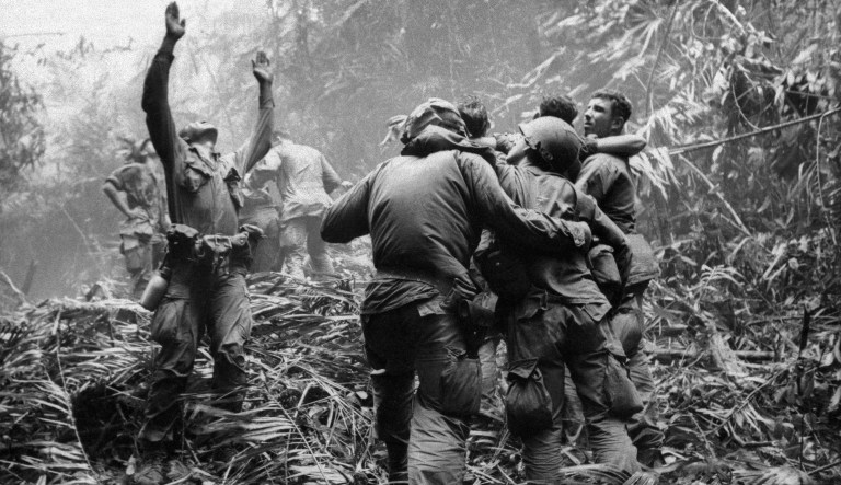 As fellow troopers aid wounded comrades guide a medevac helicopter through the jungle foliage to pick up casualties suffered during a five-day patrol. 