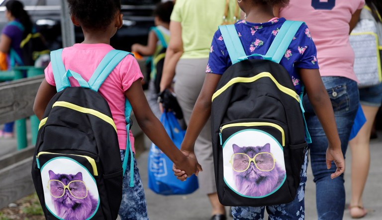 In this Aug. 15, 2015 file photo, students hold hands as they walk with their new book bags in Miami.