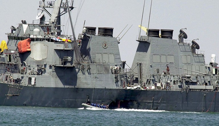 Investigators in a speed boat examine the hull of the USS Cole at the Yemeni port of Aden, after a powerful explosion ripped a hole in the U.S Navy destroyer, killing at least 17 sailors and injuring some 30 others.