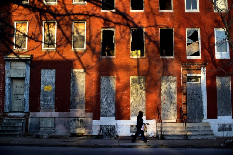A woman walks past blighted row houses in Baltimore.