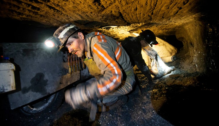 Scottie Stinson, a coal miner of 16 years, crawls through a coal mine roughly 40-inches-high while securing the roof with bolts in Welch, W.Va.