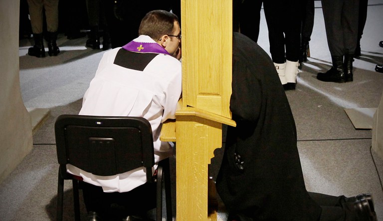 A Roman Catholic priest listens to someone's confession.