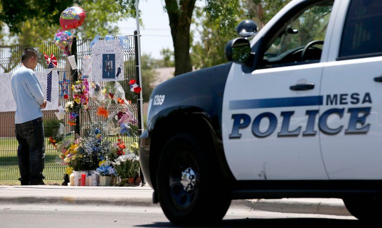 A passerby pauses at a makeshift memorial at Guerrero Park for Mesa police Officer Brandon Mendoza, who died when his vehicle collided on a Tempe, Ariz., freeway ramp after Raul Silva Corona drove 35 miles in the wrong direction on three freeways early Monday morning, on Tuesday, May 13, 2014, in Mesa, Ariz.