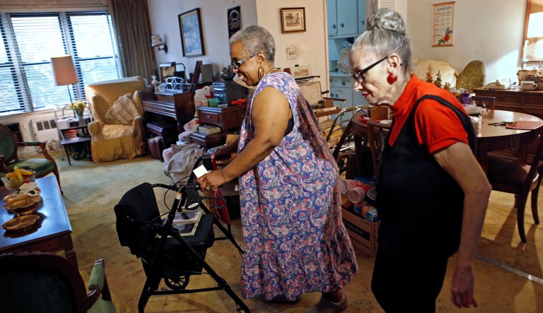 Carolyn Allen, left, a 69-year-old widow who has suffered two strokes, makes her way to the living room with roommate Marcia Rosenfeld, who owns the apartment Allen lives in New York.