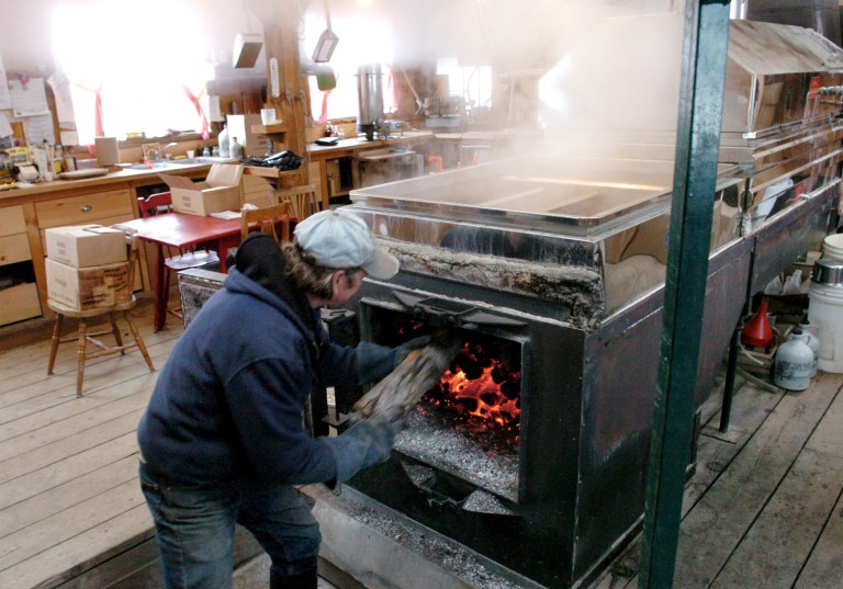 Rob Johanson, co-owner of Goranson's Farm in Dresden, Maine, adds more wood to the fire in his evaporator. Maine is one of several U.S. states where residents and maple syrup-makers alike use wood stoves, a high-emitting appliance that is expected to be the subject of a new lawsuit against the EPA.  (AP Photo/The Times Record, Paul Cunningham)