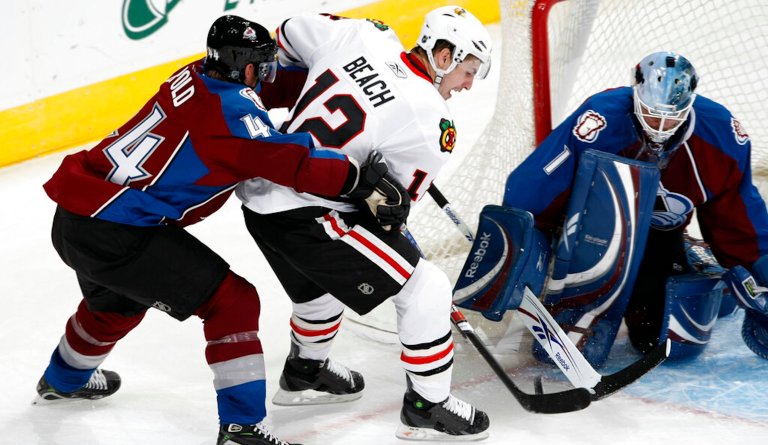 Colorado Avalanche defenseman Jordan Leopold, left, holds on to Chicago Blackhawks left winger Kyle Beach.