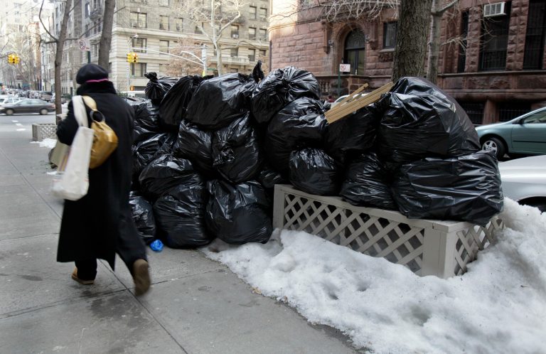 A woman walks by bags of uncollected trash on New York's Upper West Side,  Thursday, Jan. 6, 2011. New York City Mayor Eric Adams announced a new plan on Monday, Oct. 17 to delay the time when residents can place trash onto the sidewalks. (AP Photo/Richard Drew)