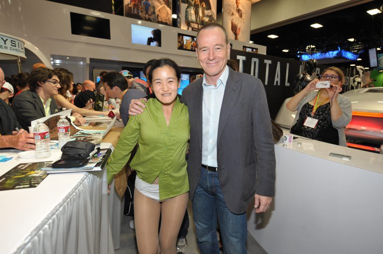 Fan Clara Kim, cosplaying as Walter White, poses for a photo with actor Bryan Cranston at AMC's 