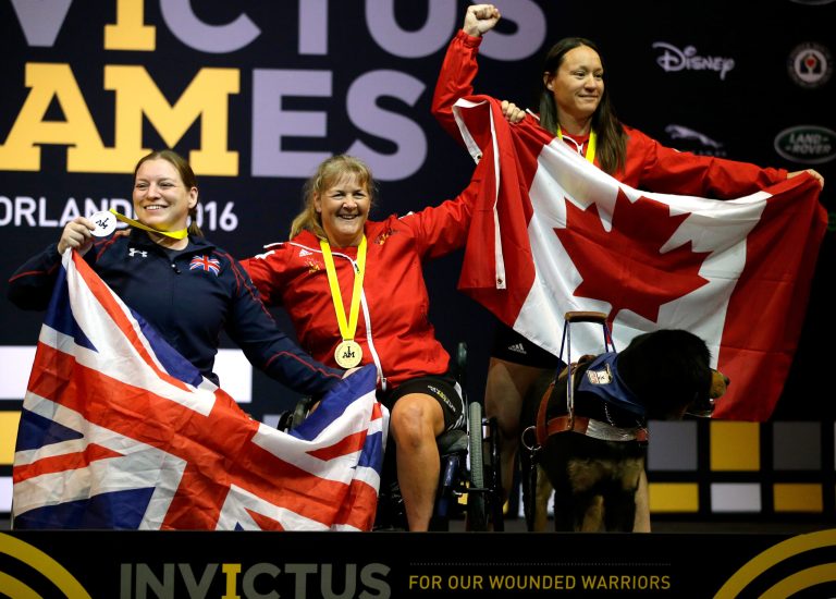 Winners in the women's heavyweight powerlift competition, from left, silver medalist Nerys Pearce, gold medalist Christine Gauthier, and bronze medalist Natacha Dupuis celebrate at the awards ceremony during the Invictus Games.