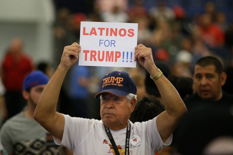 A Hispanic man holds up a sign for Republican presidential candidate Donald Trump before the start of a rally at the Anaheim Convention Center in 2016. The Committee to Defend the President is running ads to boost Trump's support in the community.