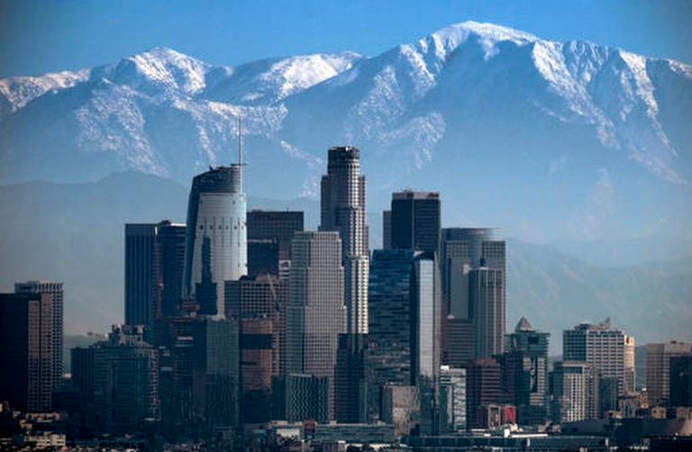 FILE - This Jan. 25, 2017 file photo shows a snow covered Mount Baldy, the highest peak among the San Gabriel Mountains behind downtown Los Angeles.  (AP Photo/Richard Vogel, File)