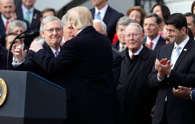 President Donald Trump greets Senate Majority Leader Mitch McConnell (R-KY) during a bill passage event on the South Lawn of the White House in Washington on Dec. 20, 2017, to acknowledge the final passage of tax cut legislation by Congress, as House Speaker Paul Ryan (R-WI) watches at right.