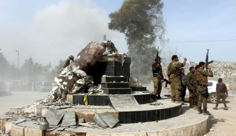 Turkey-backed Free Syrian Army soldiers celebrate around a statue of Kawa, a mythology figure in Kurdish culture, after they have destroyed it in the city center of Afrin, northwestern Syria, early Sunday, March 18, 2018. Turkey's President Recep Tayyip Erdogan said Sunday that allied Syrian forces have taken "total" control of the town center of Afrin, the target of a nearly two-month-old Turkish offensive against a Syrian Kurdish militia, which said fighting was still underway. Erdogan said the Turkish flag and the flag of the Syrian opposition fighters have been raised in the town, previously controlled by the Kurdish militia known as the People's Defense Units, or YPG.