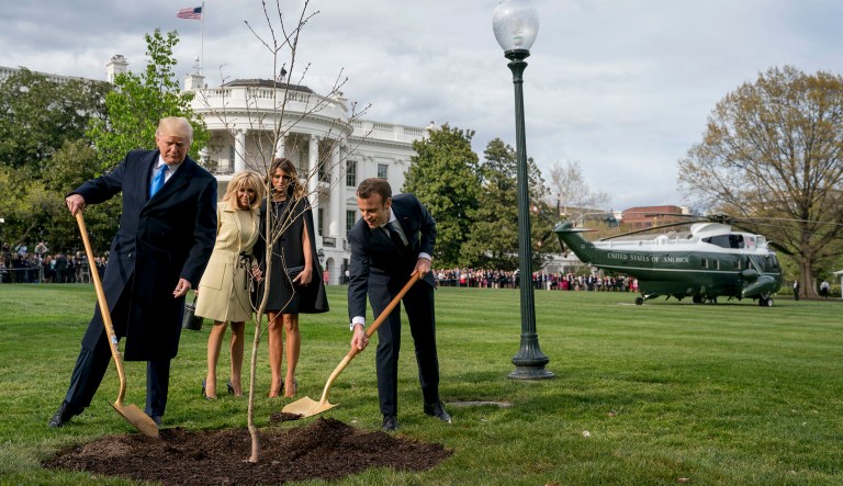 First lady Melania Trump and Brigitte Macron watch as President Trump and French President Emmanuel Macron participate in a tree planting ceremony on the South Lawn of the White House in Washington.