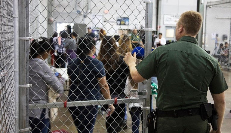 A U.S. Border Patrol agent watches as people who've been taken into custody related to cases of illegal entry into the United States stand in line at a facility in McAllen, Texas.