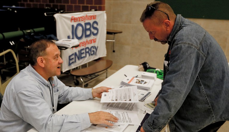 A recruiter in the shale gas industry, left, speaks with an attendee of a job fair. Economists have estimated that 195,000 jobs were added last month and that the unemployment rate remained at an 18-year low of 3.8 percent, according to data provider FactSet.  