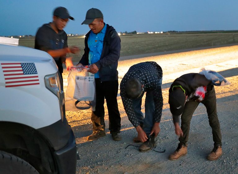 Four Guatemalan nationals consisting of two men and a pair of 12 and 13-year-old boys, remove their shoe laces and personal items after being arrested by a U.S. Customs and Border Patrol agent Wednesday, July 18, 2018 in Yuma, Ariz. Recent crossers are infected with the coronavirus.