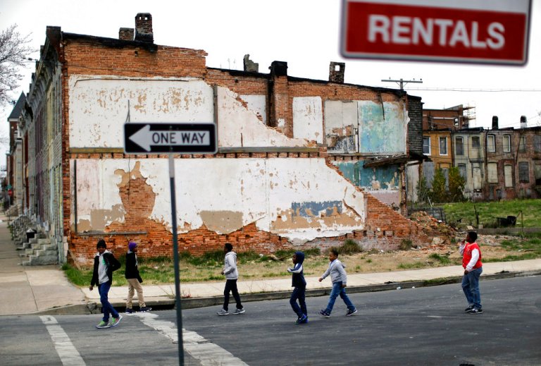 In this April 4, 2013 file photo, a group of boys walk past a partially collapsed row house in Baltimore. 