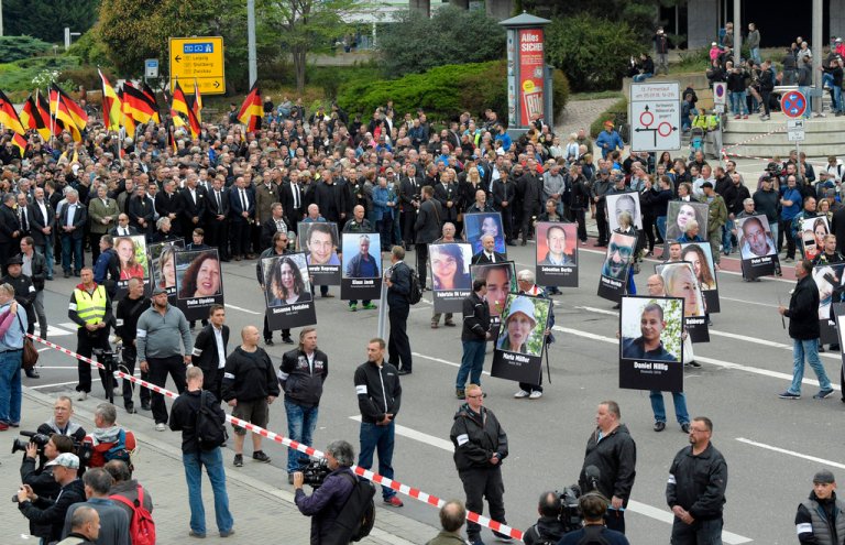 Demonstrators hold photos of people they claim have been killed by migrants during a demonstration in Chemnitz, eastern Germany, Saturday, Sept. 1, 2018, after several nationalist groups called for marches protesting the killing of a German man last week, allegedly by migrants from Syria and Iraq. (AP Photo/Jens Meyer)