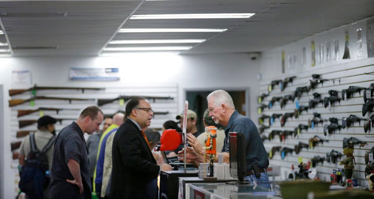 FILE - In this Dec. 9, 2015, file photo, sales associate Mike Conway, right, shows Paul Angulo a pistol at Bullseye Sport gun shop in Riverside, California.