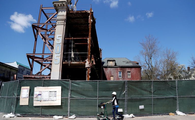 A woman walks along side the facade of a former bank during reconstruction in an  âopportunity zoneâ in Newark, N.J. The administration says the initiative has raised $75 billion in private investment for underprivileged communities