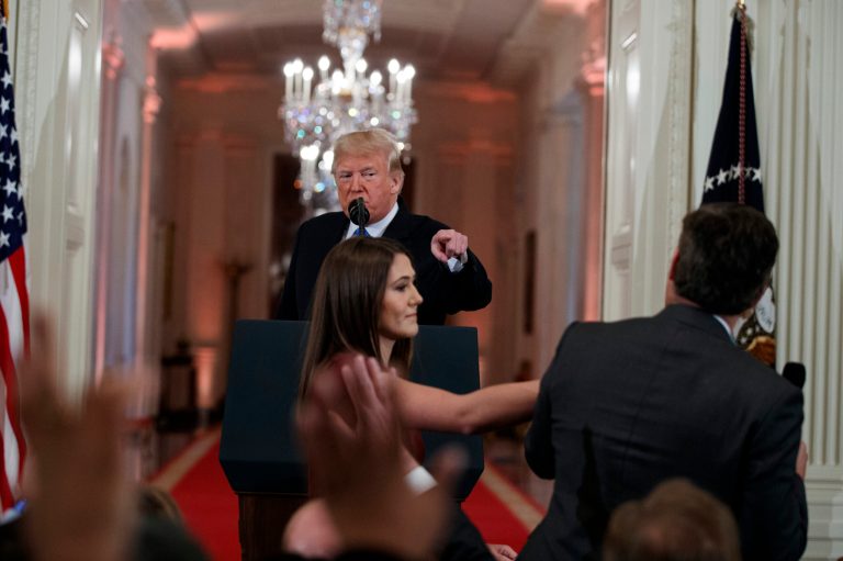 In this Nov. 7, 2018 file photo, President Donald Trump watches as a White House aide reaches to take away a microphone from CNN journalist Jim Acosta during a news conference in the East Room of the White House in Washington.