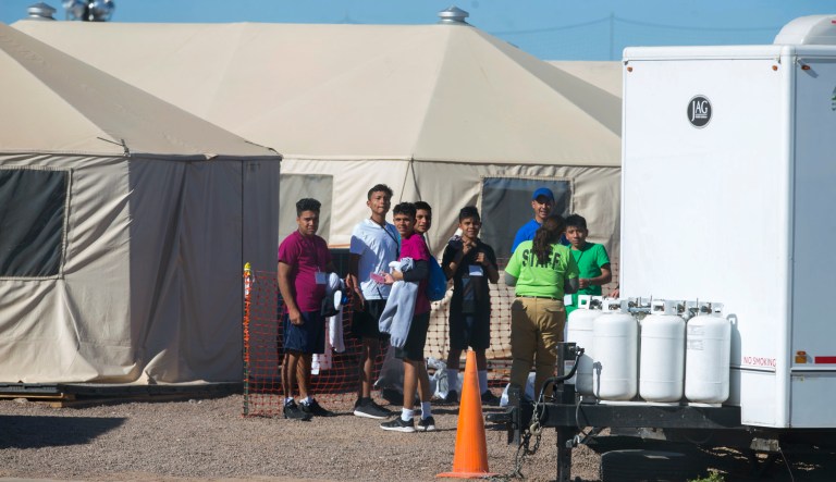 In this Nov. 15, 2018, photo provided by Ivan Pierre Aguirre, migrant teens held inside the Tornillo detention camp look at protesters waving at them outside the fences surrounding the facility in Tornillo, Texas.
